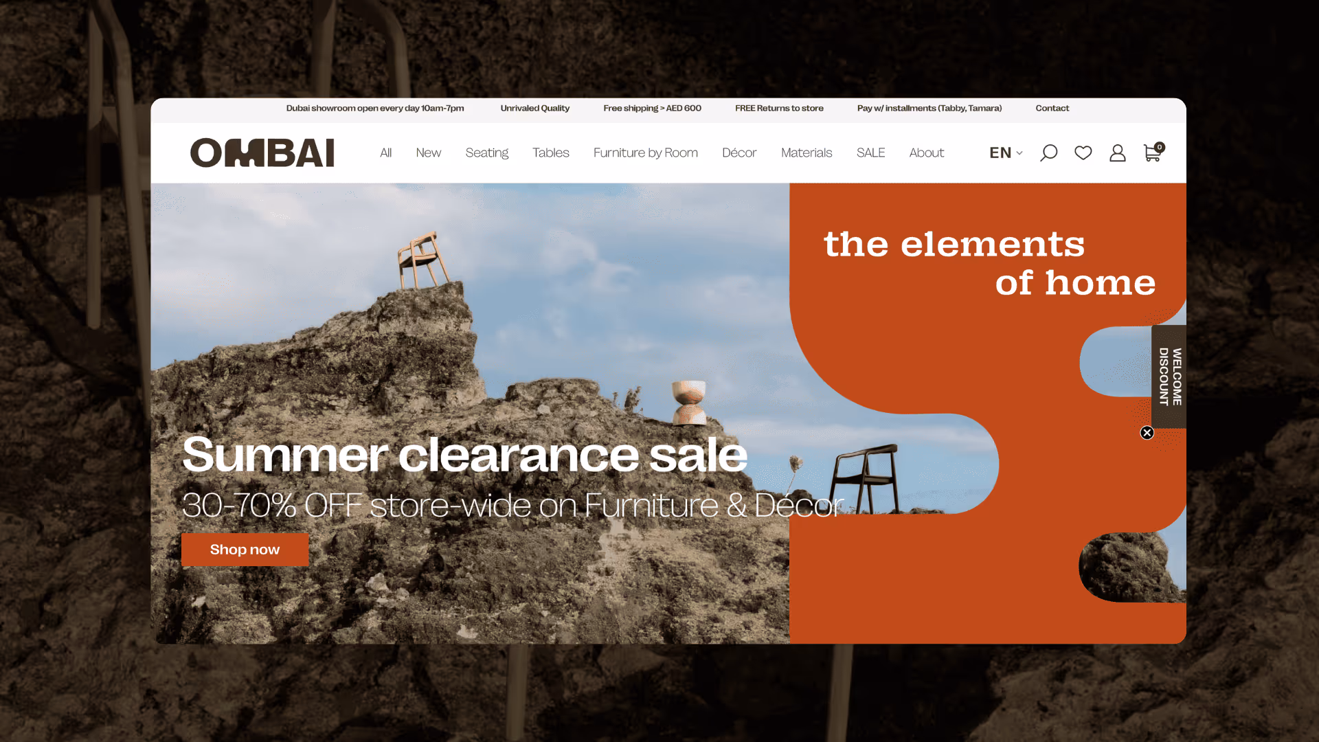 Website homepage showcasing a summer clearance sale with furniture on rocky terrain against a blue sky and text reading 'the elements of home'.