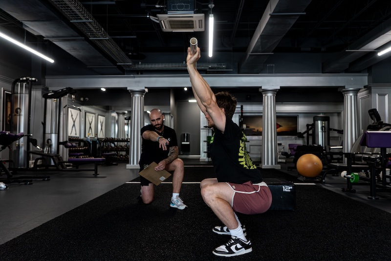 X Shadyside coach pointing at man squatting with a barbell without weights