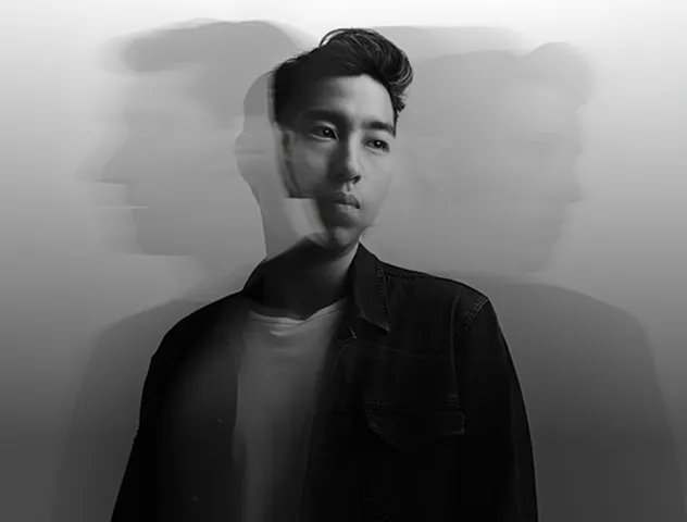 Black and white portrait of a contemplative young man with blurred multiple exposures of his profile behind him.