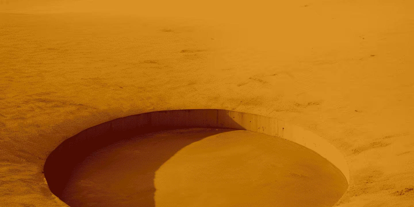 Blurry close-up of a golf hole on a sand-covered putting green.