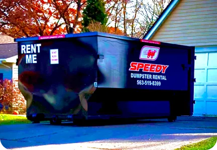 Large blue Speedy dumpster rental container parked on residential street