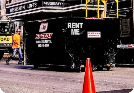 Black dumpster with Speedy Dumpster Rental sign near urban street
