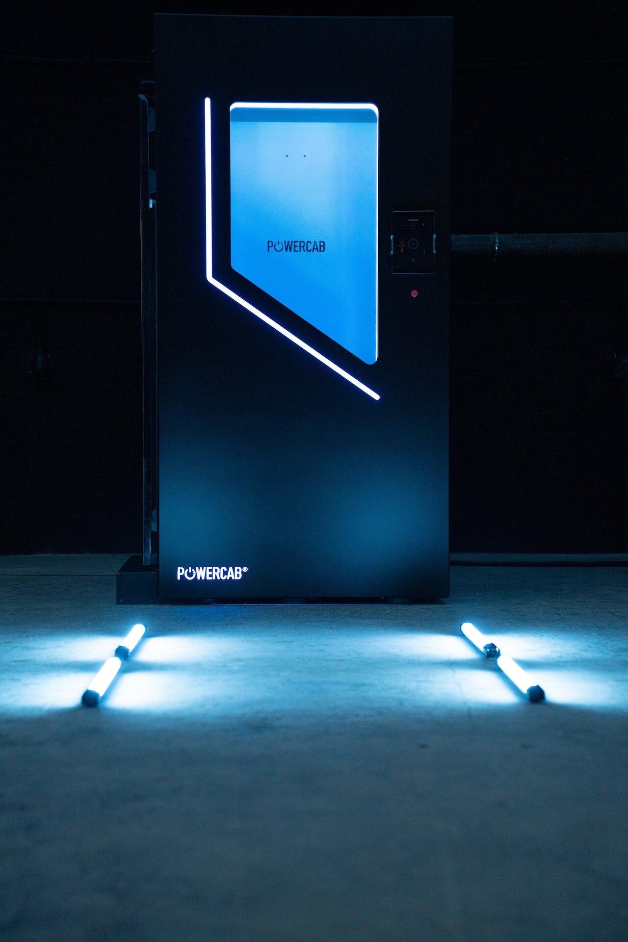 Schwarze Powercab-Einheit mit blauer Beleuchtung in einem dunklen Raum auf Betonboden.