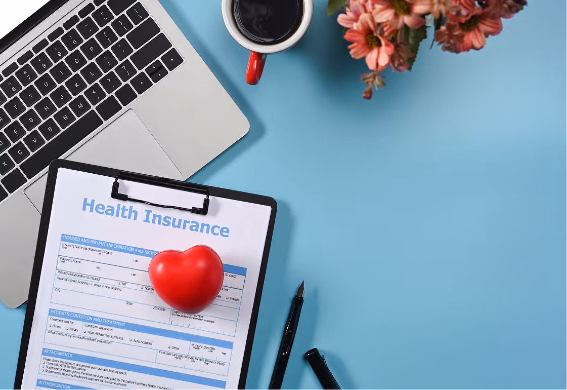 Laptop with health insurance forms, stethoscope, and apple symbolizing HMO and wellness programs.