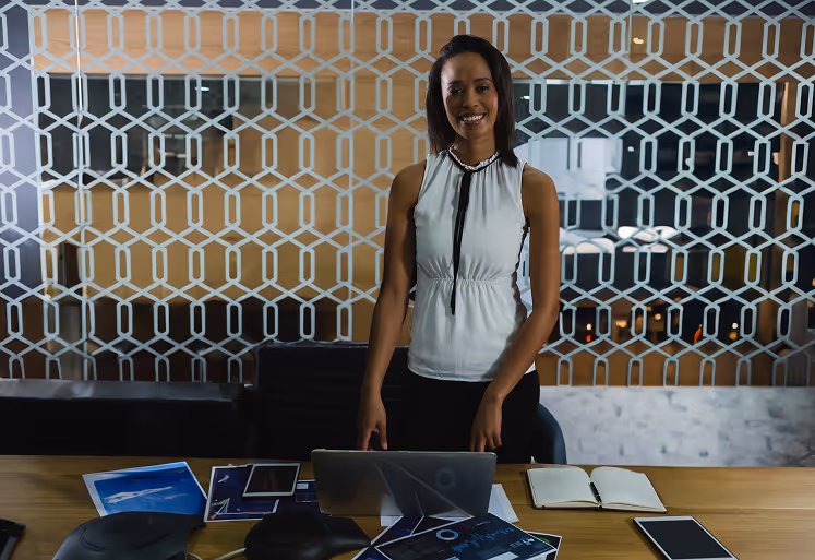 Professional woman standing in a modern office, smiling confidently before a wellness meeting.