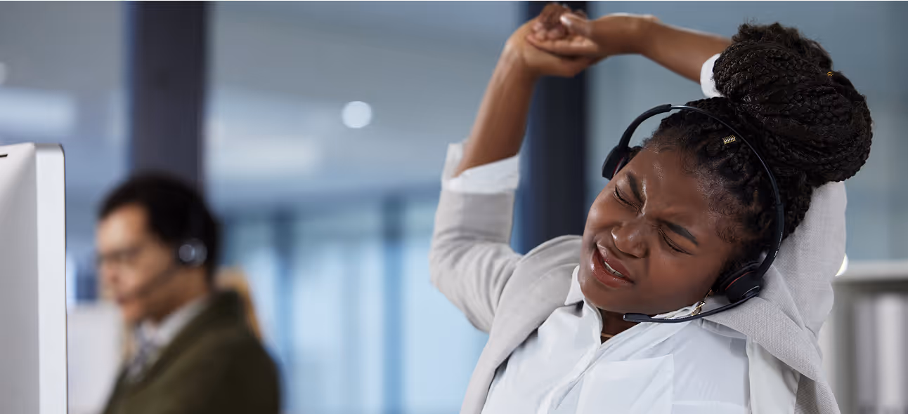 Employee stretching arms at her desk as part of workplace wellness routine.