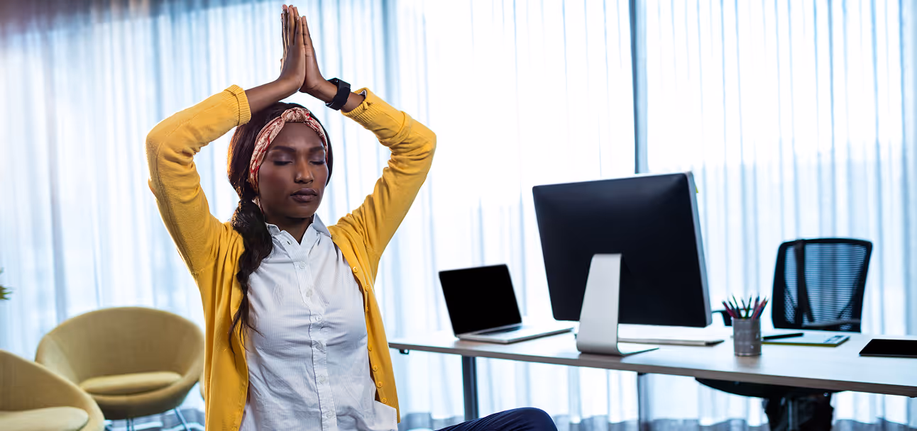 Businesswoman practicing seated desk stretches during a break in the office.