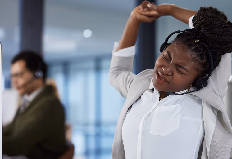 Employee stretching arms at her desk as part of workplace wellness routine.