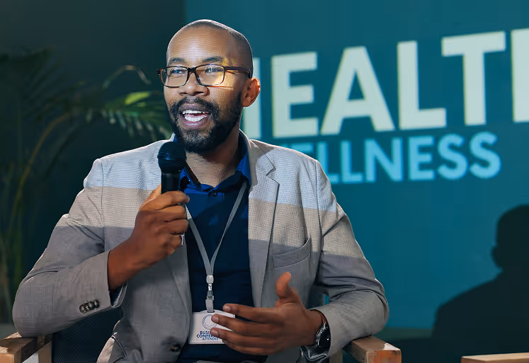 Male speaker presenting at a health and wellness event with HealthFusion branding in the background.