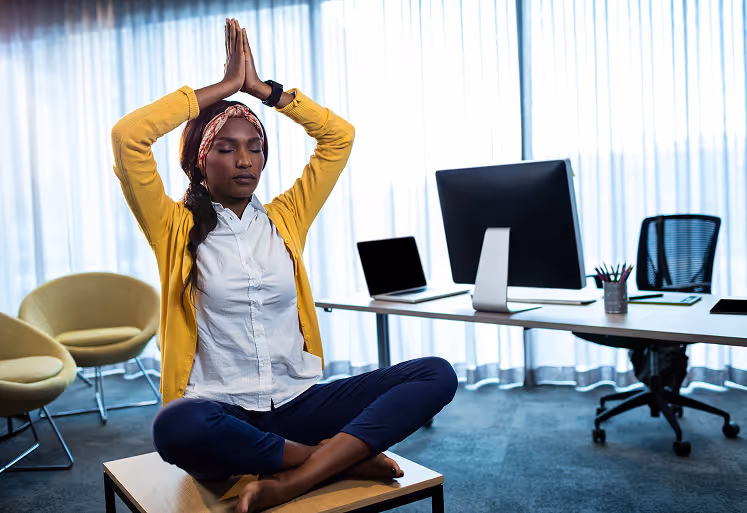 Businesswoman practicing seated desk stretches during a break in the office.
