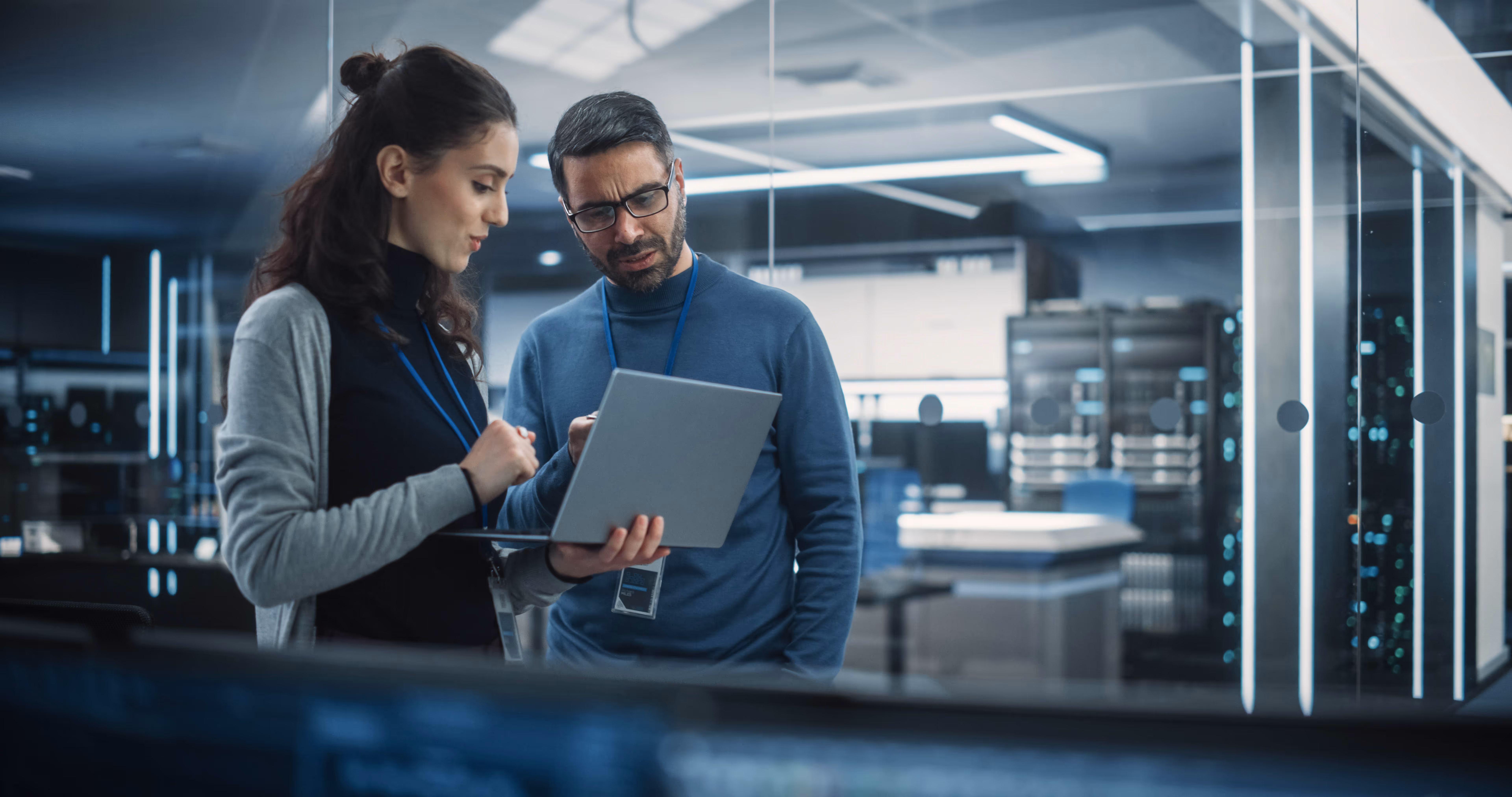 a women and a man working on a laptop in a server room