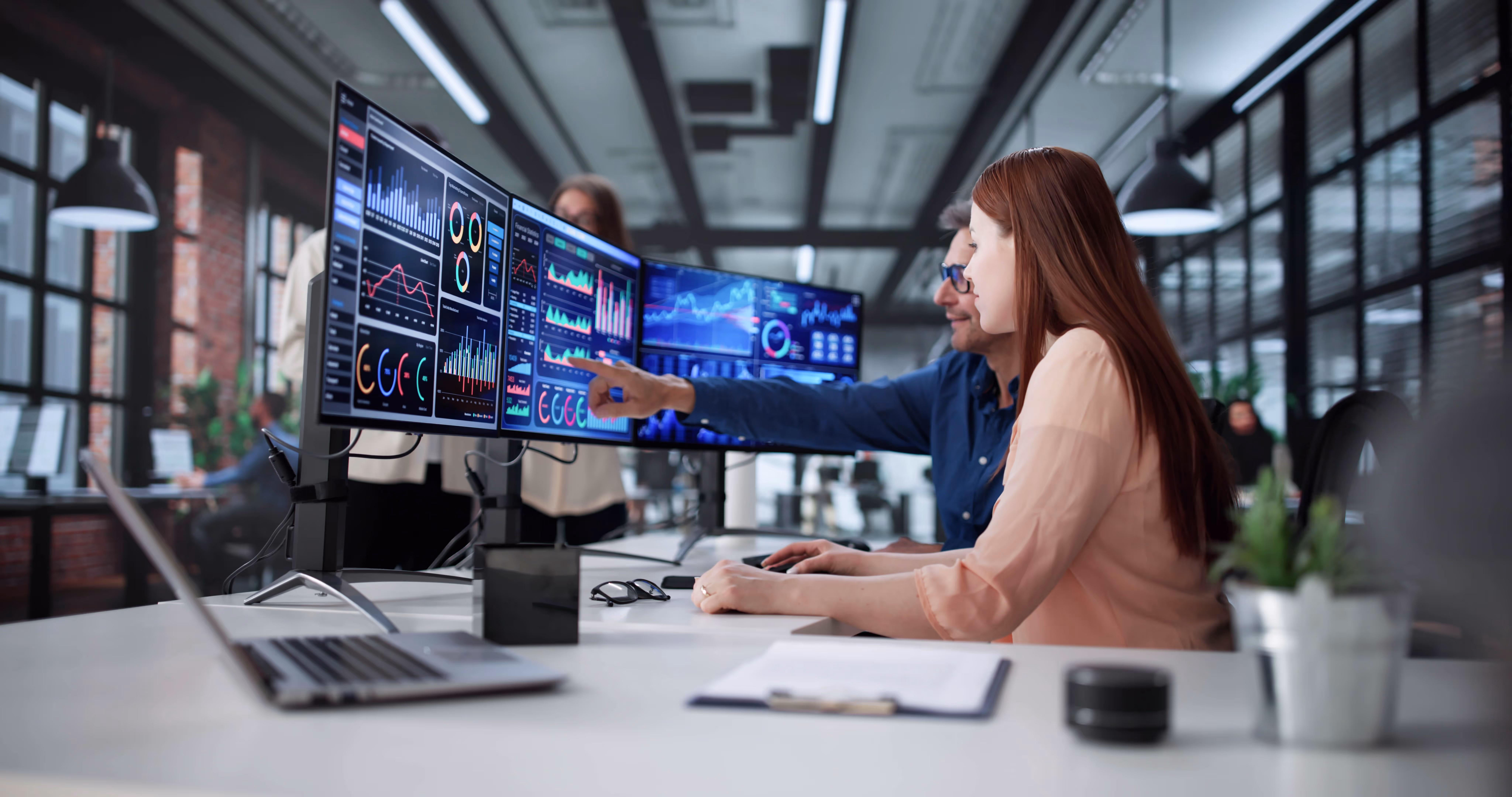 women working on 3 monitors