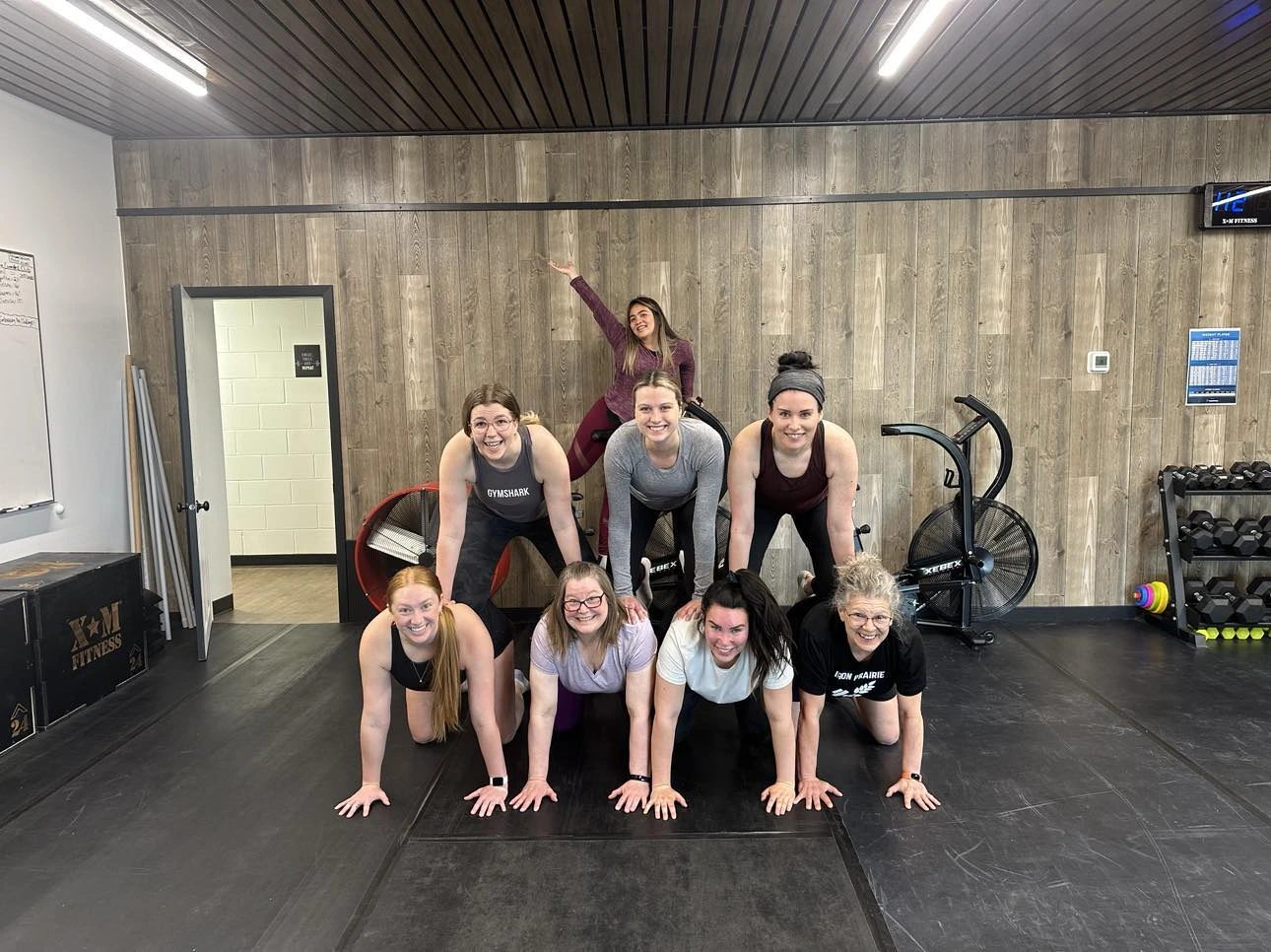A group of women smiling and posing for a photo inside Iron Prairie Strength Lab gym in Moosomin, SK.