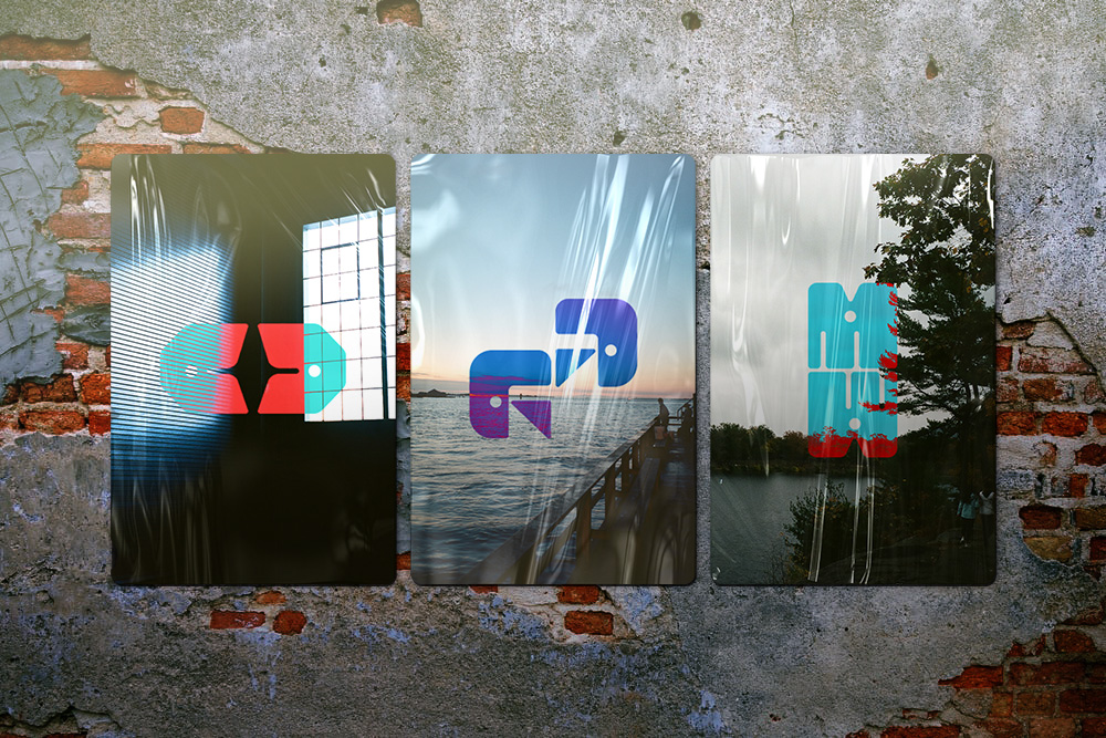Three photographic posters with colorful abstract symbols mounted on a weathered brick wall.