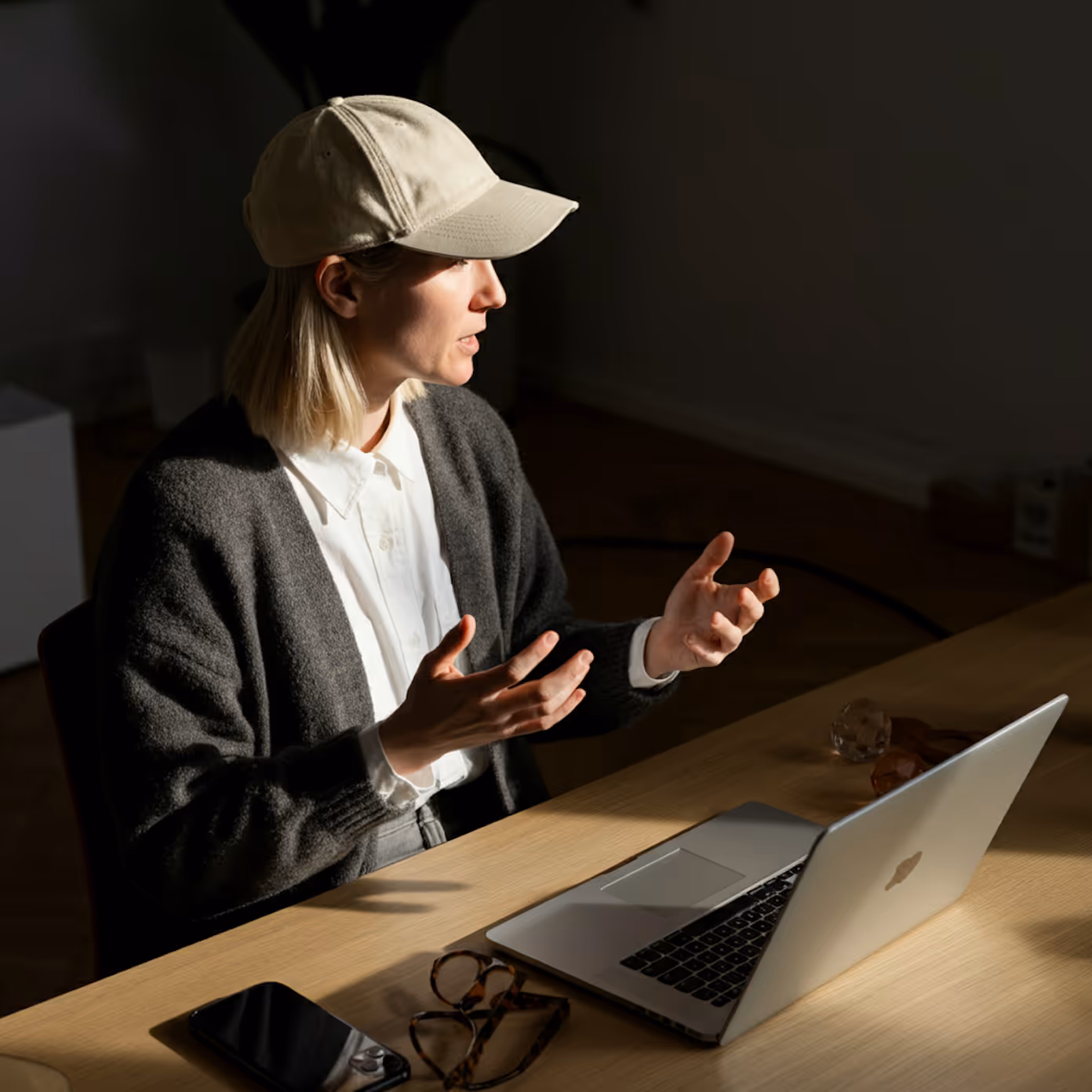 Dame is in overleg in een professionele setting. Ze kijkt weg van het scherm met een laptop voor haar.  