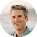 Portrait of a smiling man with short, spiky light brown hair wearing a green shirt.