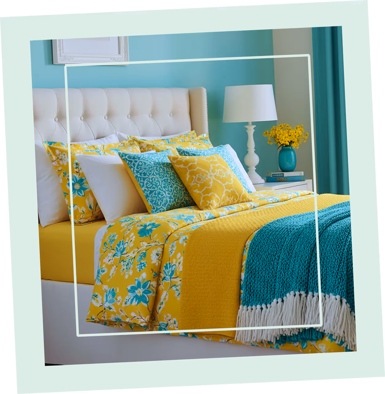 "Modern bedroom with yellow and teal bedding, decorative cushions, and a vase of yellow flowers."