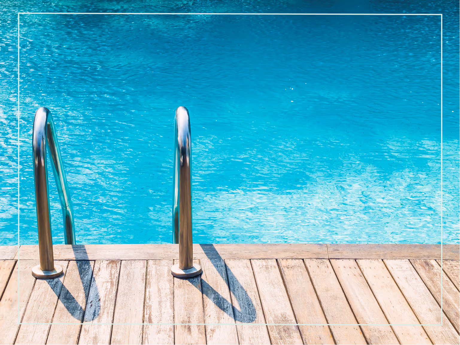 "Metal pool ladder leading into a turquoise blue swimming pool beside a wooden deck."