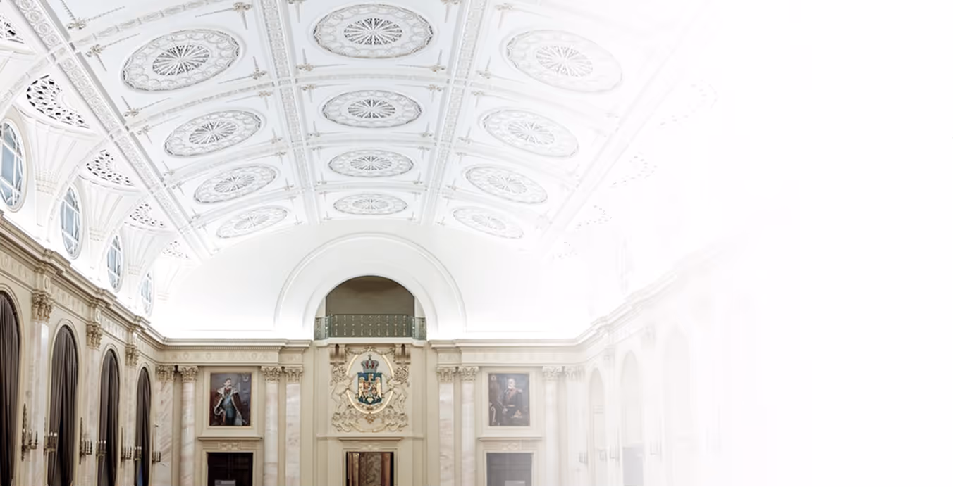 “Spacious neoclassical dining hall with marble columns, vaulted ceiling with ornate plaster medallions, and historic portraits on the walls.”