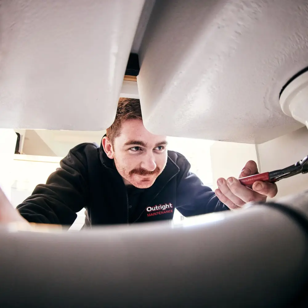 Pat fixing a leak under the sink