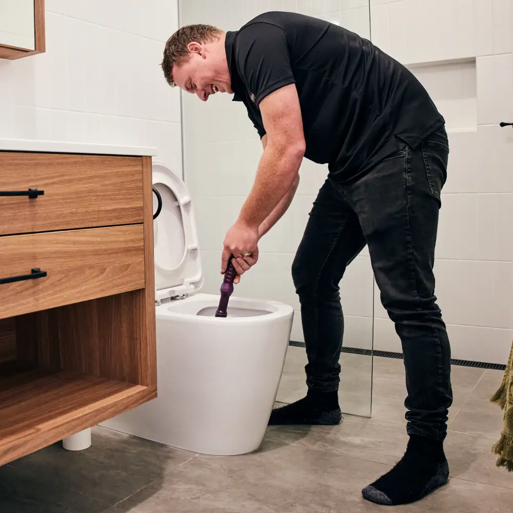 Plumber plunging a toilet