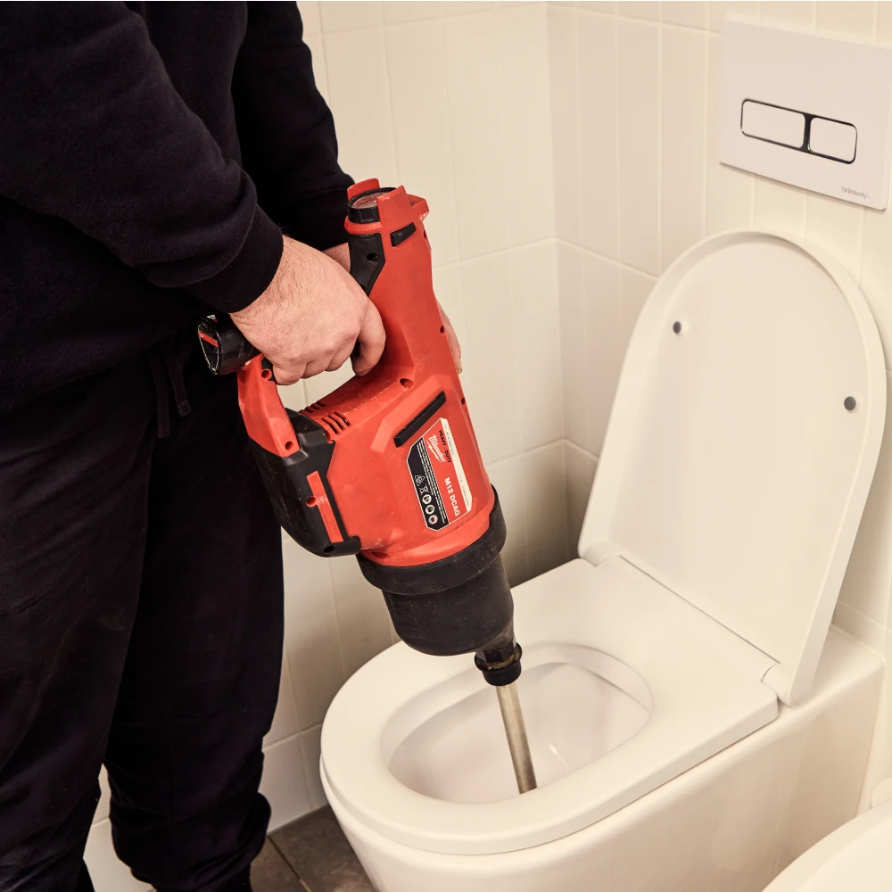 Person unclogging a toilet with a plunger