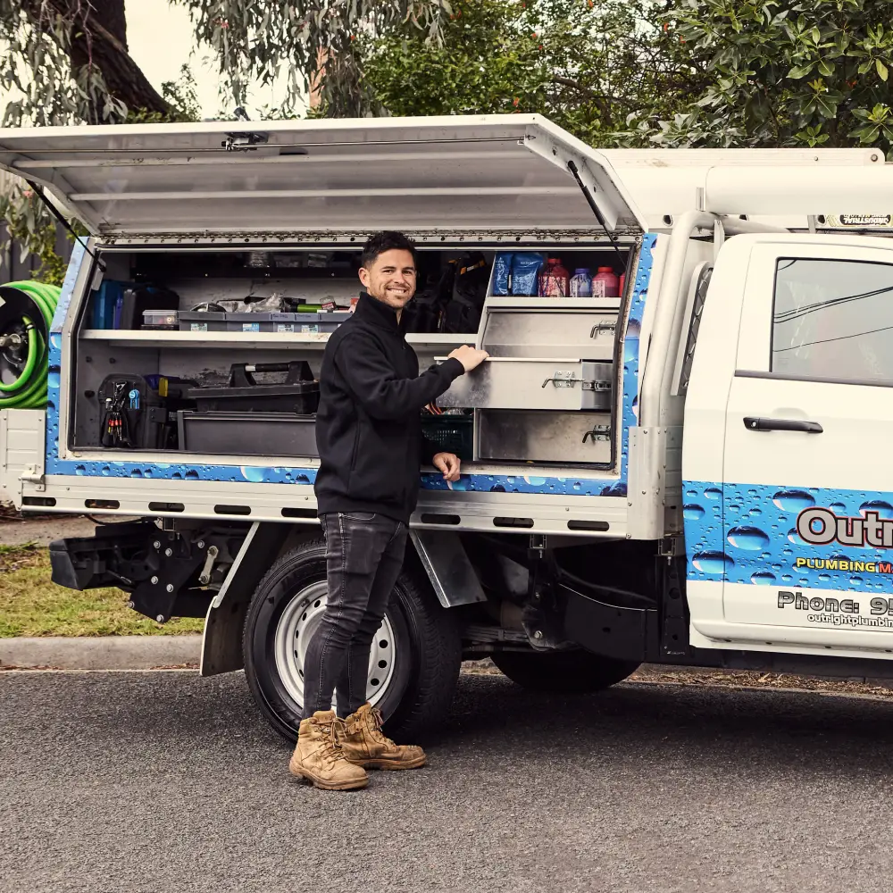 Plumber standing beside a service truck happily preparing to perform a leak repair
