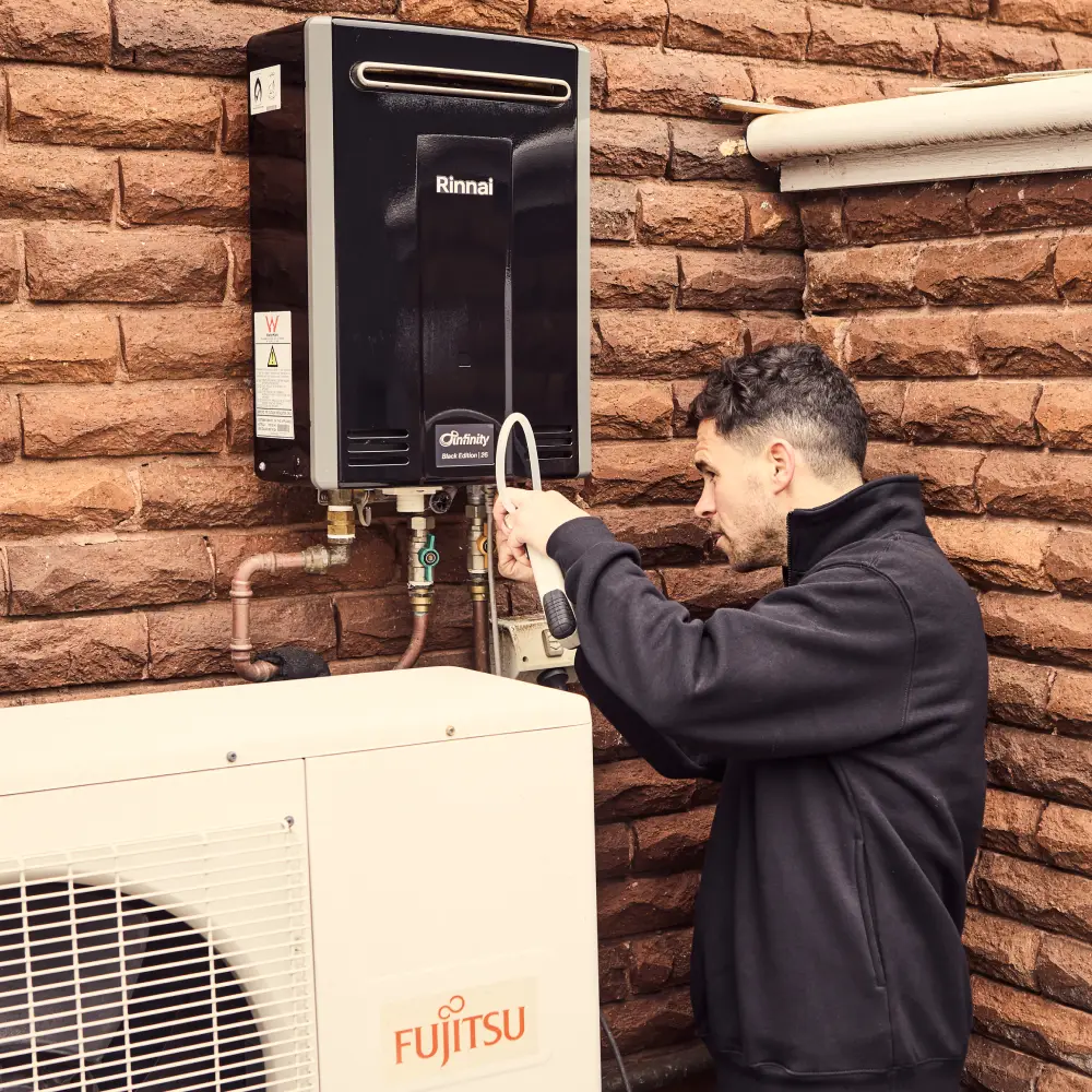 Technician checking Rinnai water heater and Fujitsu heat pump system