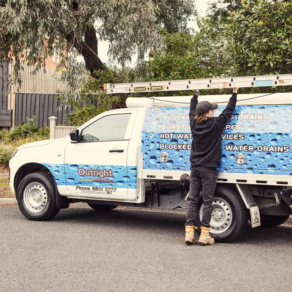 A plumber fetches the ladder from their truck’s roof rack
