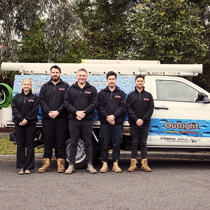 Five Outright employees posing in front of service truck in matching uniforms