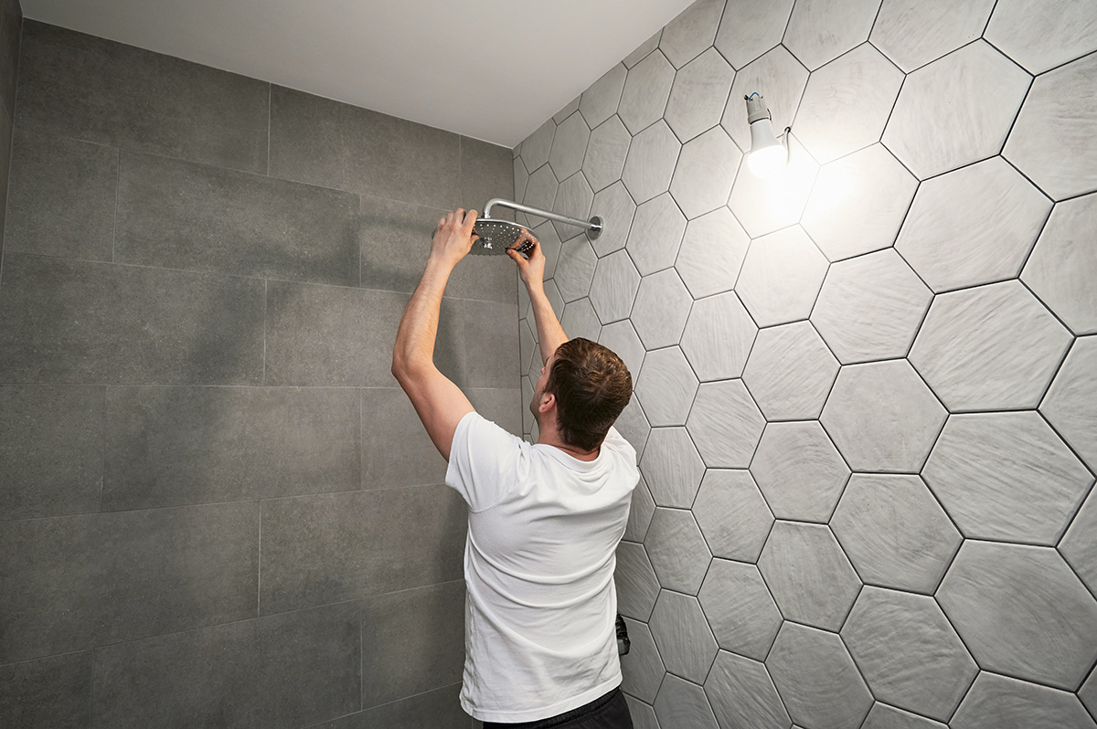 A licensed plumber fitting the showerhead in a newly plumbed-in shower. Outright Plumbing handles shower installations for homes across Melbourne.