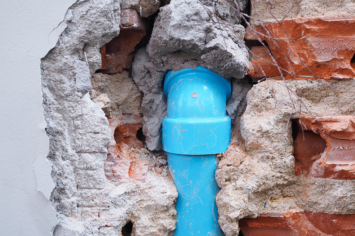 A damaged blue PVC water pipe, surrounding by cracked concrete. This is in a Melbourne home Outright Plumbing visited, where we had to repair the exposed plumbing.