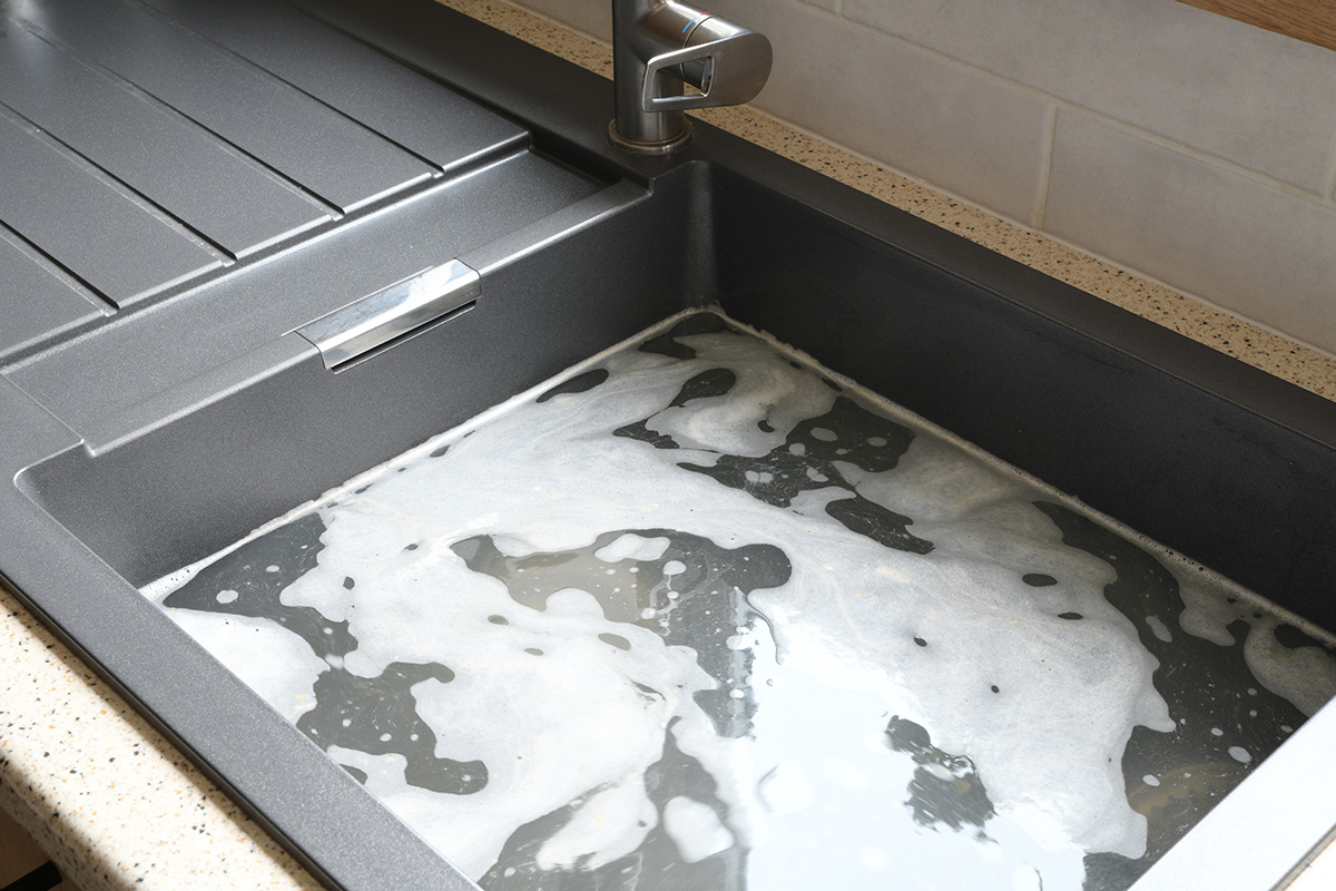 A clogged and flooding kitchen sink. Tenants may be responsible for blocked drains if they’re clogged by everyday household waste.