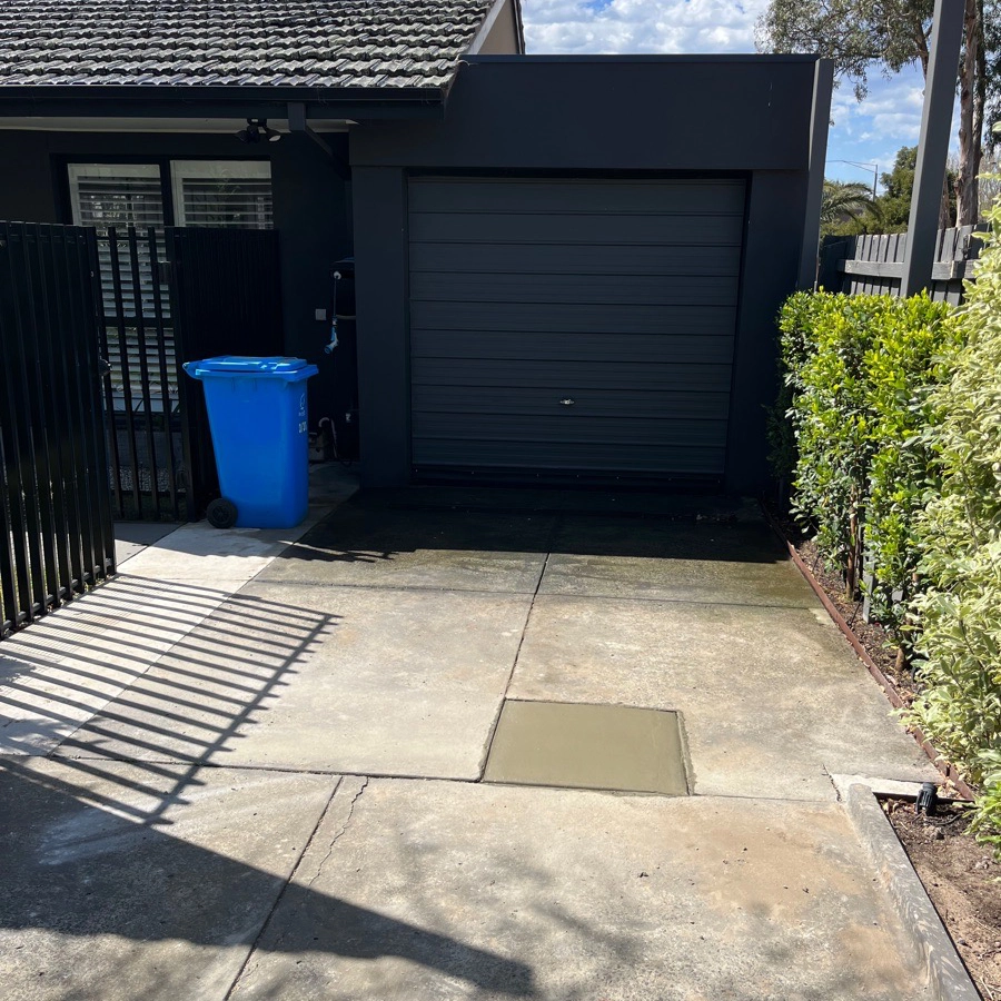 Driveway fully repaired with new concrete patch near garage.
