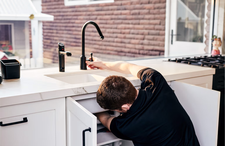 Outright Plumbing staff member installing a new tap in a sink