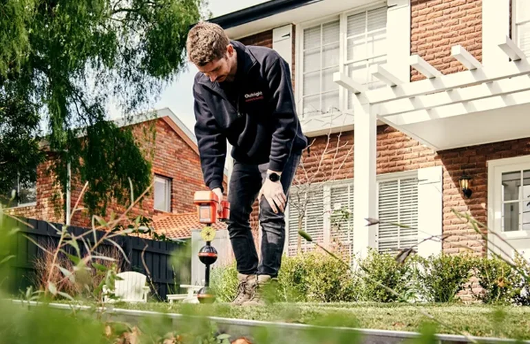 Outright Plumbing plumber using an orange pipe locator on a lawn