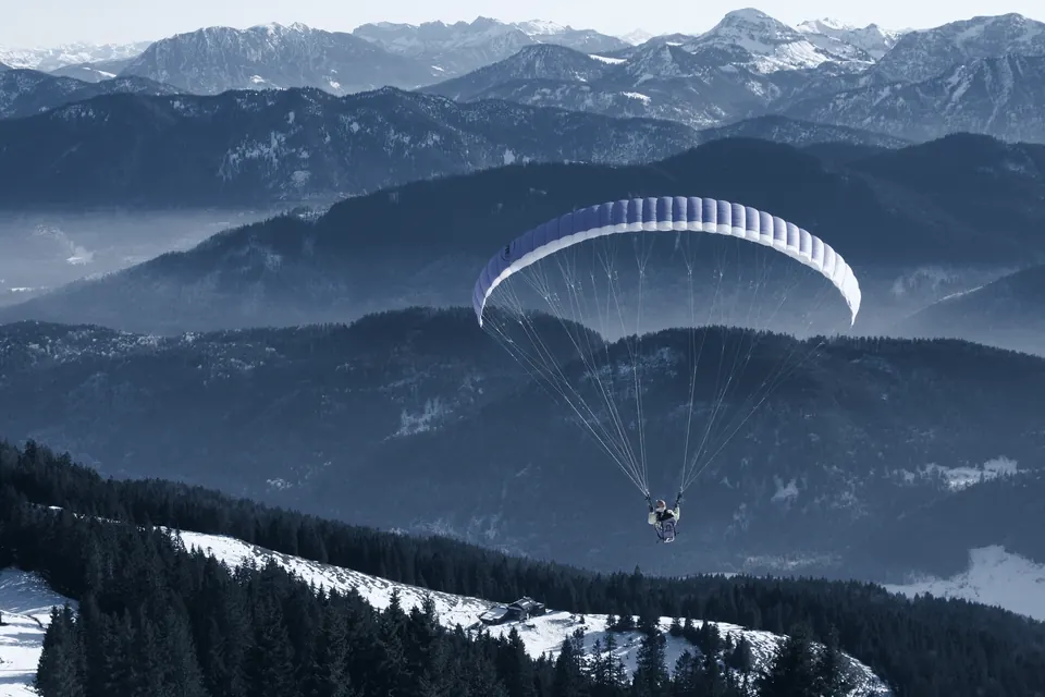 Parapente au-dessus de vallées boisées dans la brume