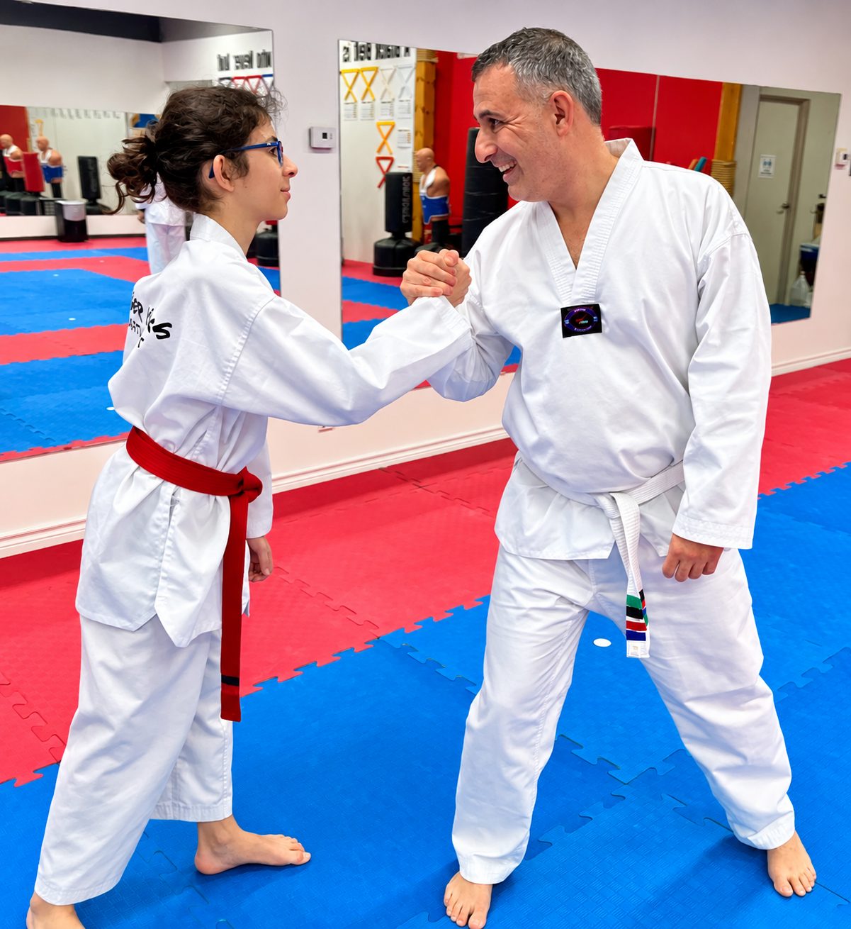 A student and an adult shaking hands after training at Tiger Kicks Martial Arts