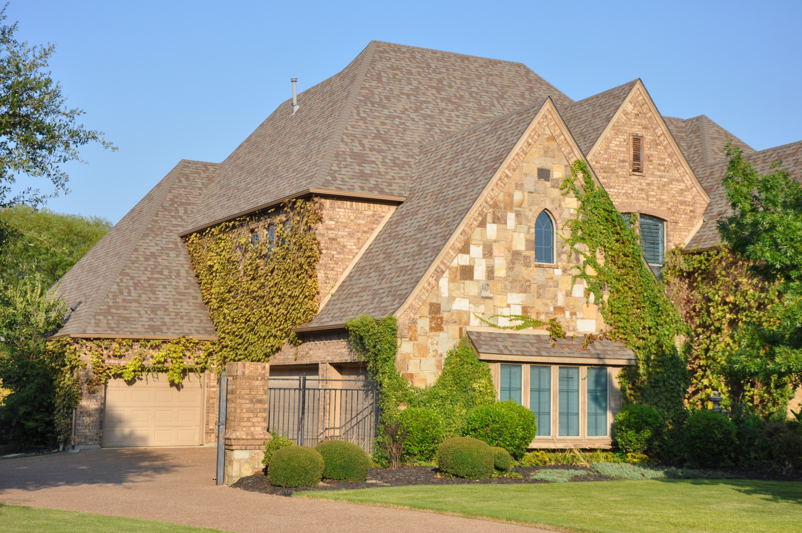 Two-story stone home with newly installed asphalt roof in Southlake TX