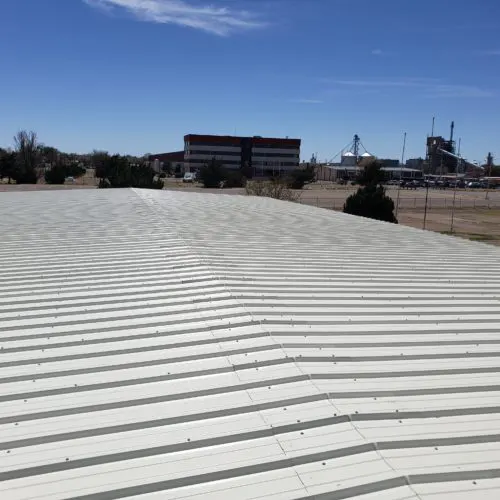 Metal commercial roof in North Dallas under clear blue sky, showcasing emergency repair readiness.
