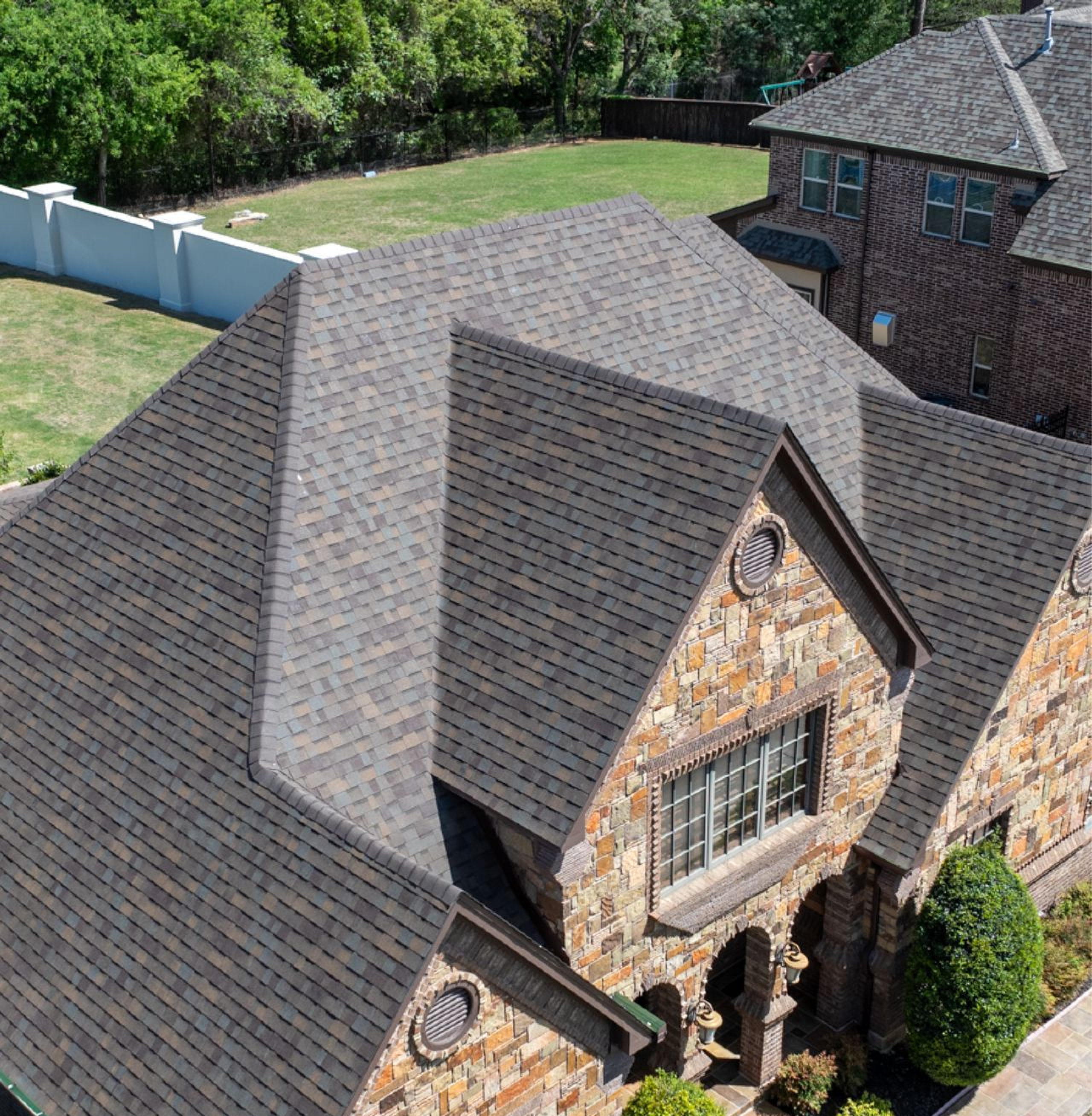 Aerial view of stone home with newly repaired asphalt shingle roof in Southlake TX