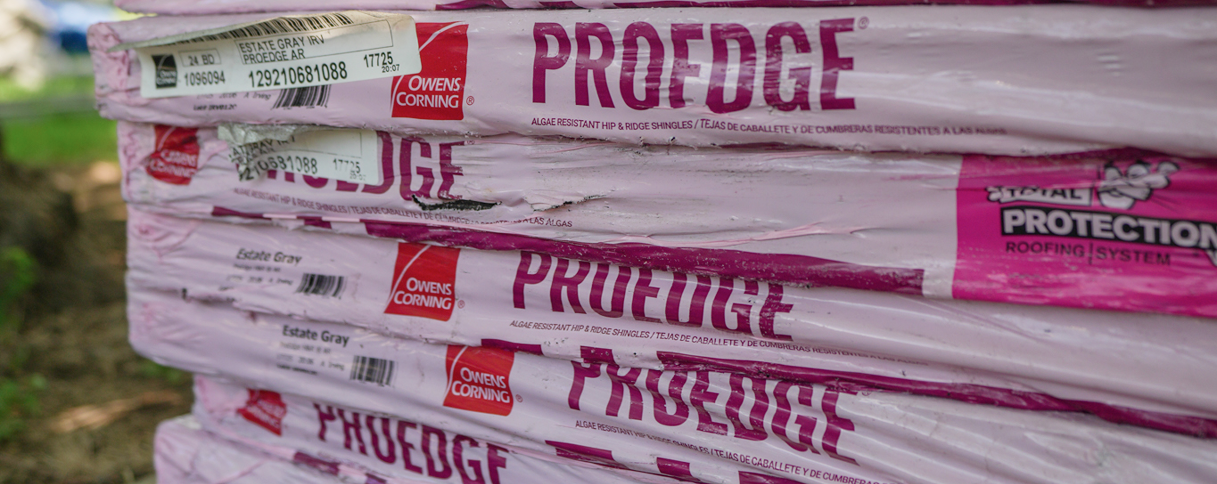 Owens Corning roofing material bundles stacked for installation by CLC Roofing, featuring algae-resistant hip and ridge shingles.
