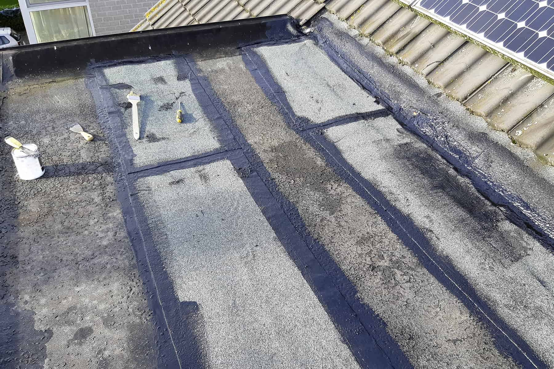 Close-up view of repaired flat roof surface with asphalt patches in Southlake TX