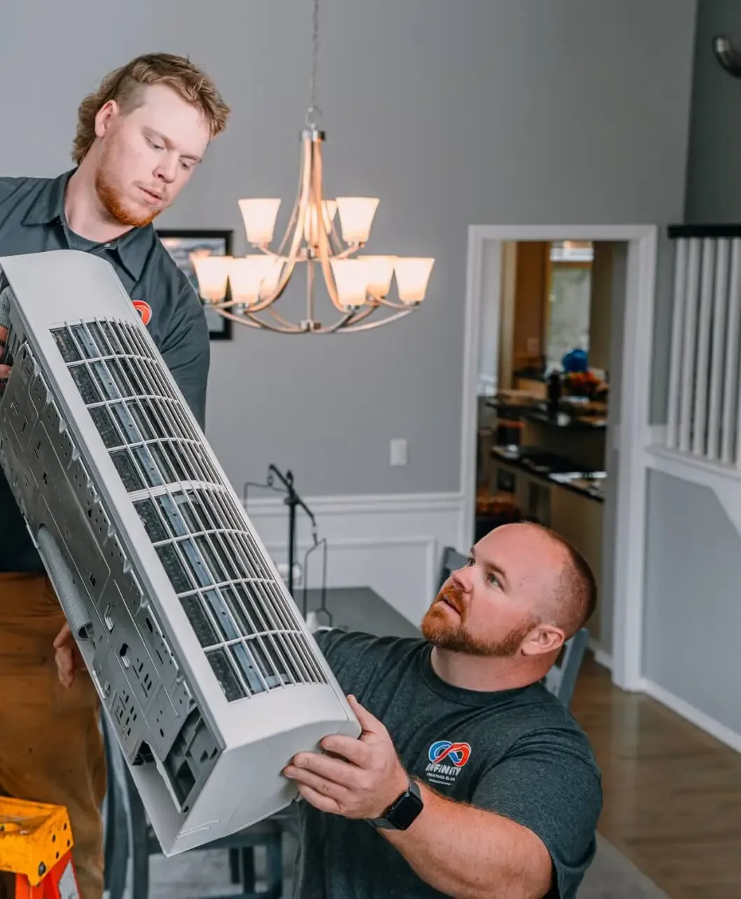 Two HVAC technicians are installing an air conditioning unit in a home.