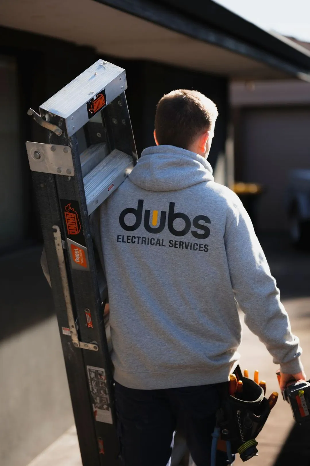 An electrician carrying a ladder