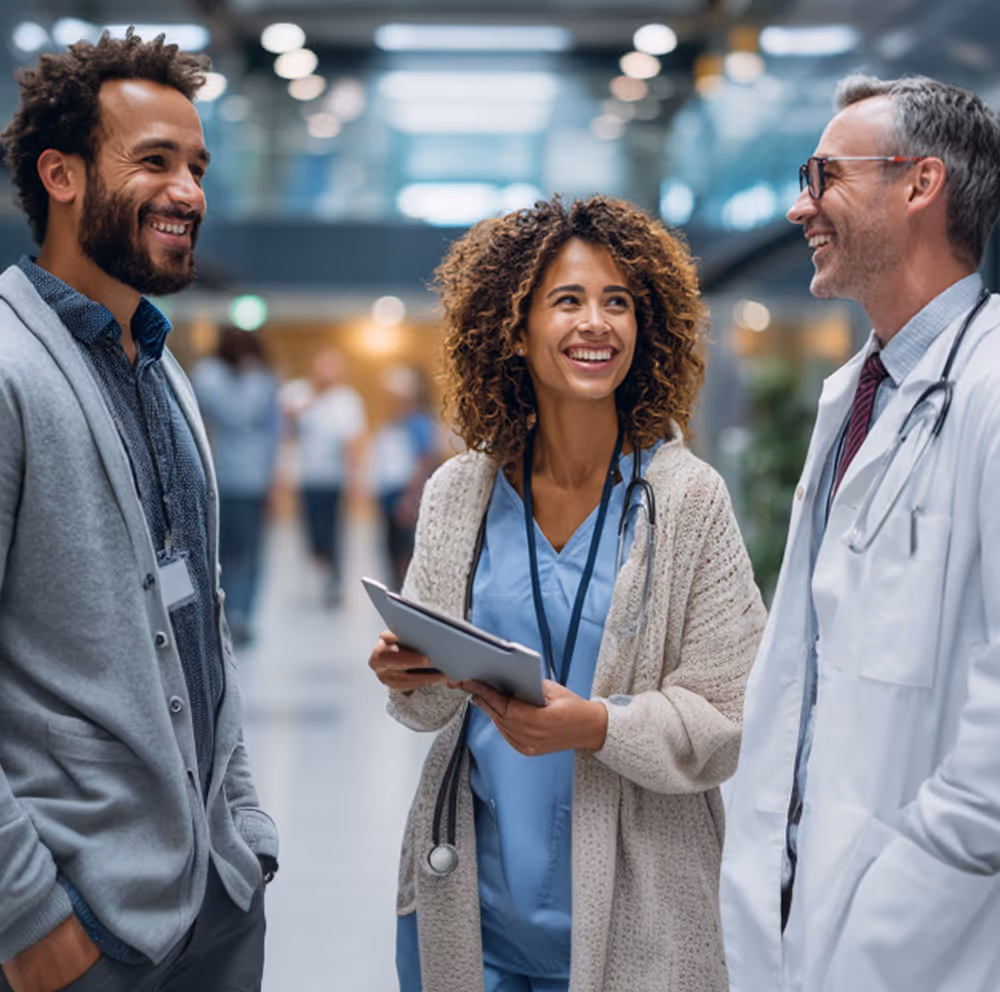 Group of healthcare professionals standing together in a hospital corridor, smiling and discussing patient care