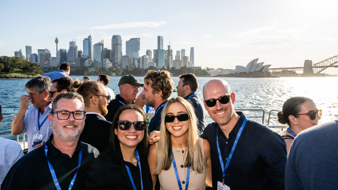 Group of four people smiling with Sydney city in the backdrop on the Harbour