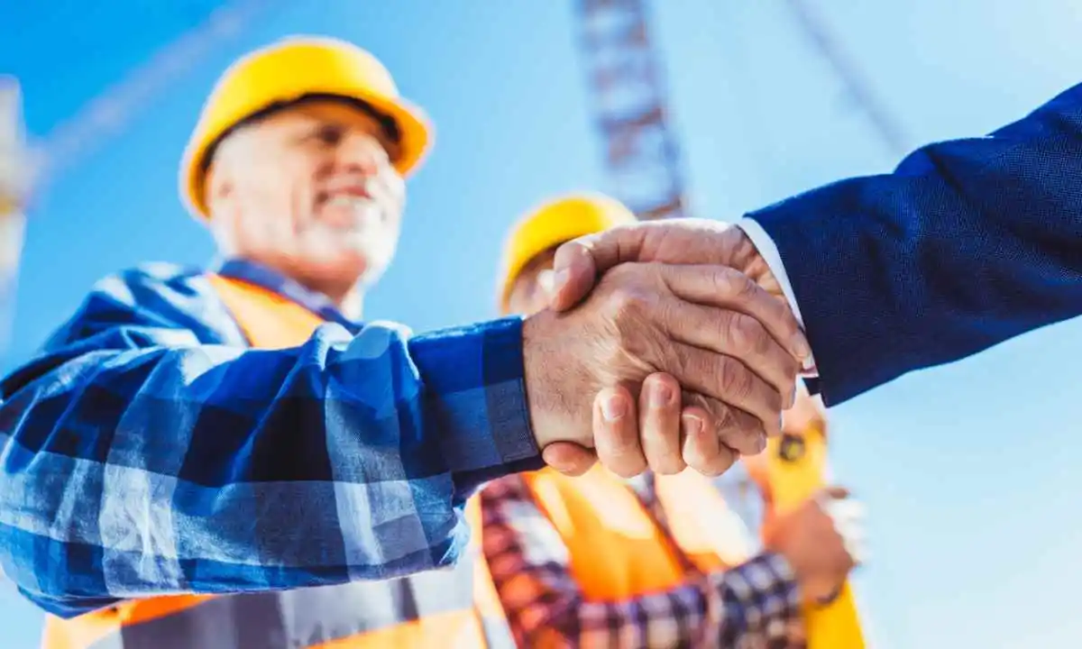Construction worker shaking hands with someone in a suit
