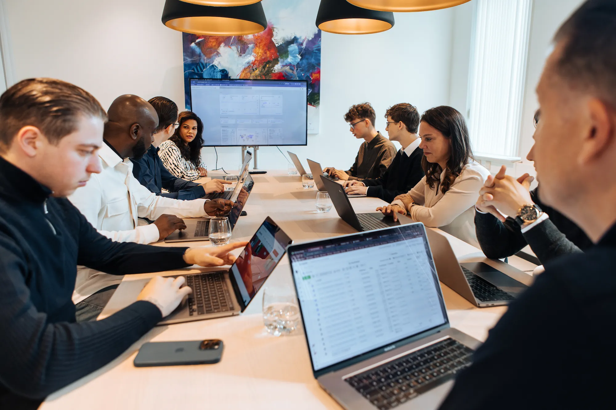 Team aan het werk aan een lange tafel met laptops