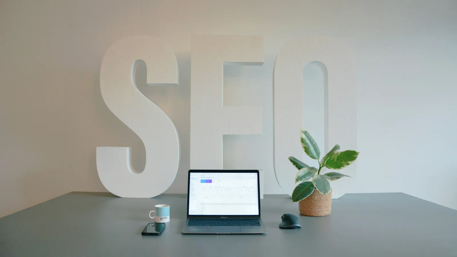 Grote SEO-letters achter een laptop op een bureau